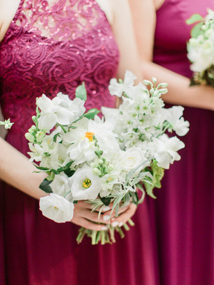 Bridesmaids holding a beautiful white flower bouquet at a wedding