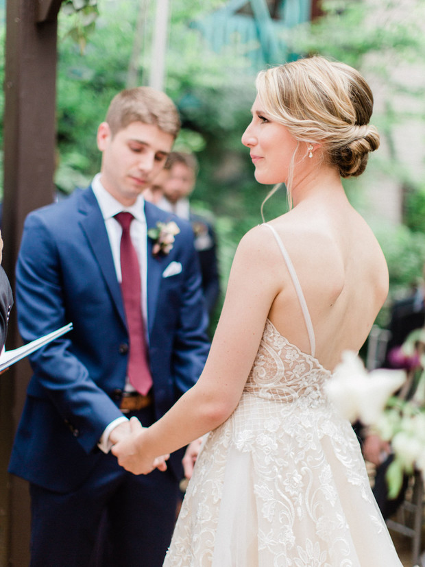 Bride and groom holding hands at wedding ceremony, looking hopeful