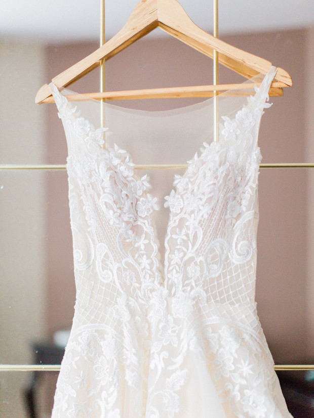 Elegant ivory lace wedding dress on a wooden hanger ready for a bride