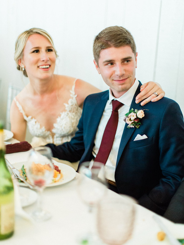 Bride and groom smiling at a wedding reception table