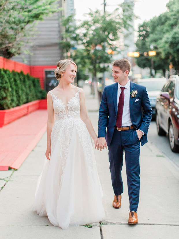 Newlyweds walk hand in hand after wedding, city scene