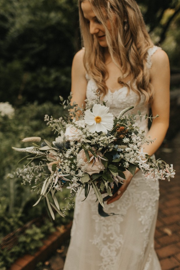 Bride in white dress holds a beautiful floral wedding bouquet