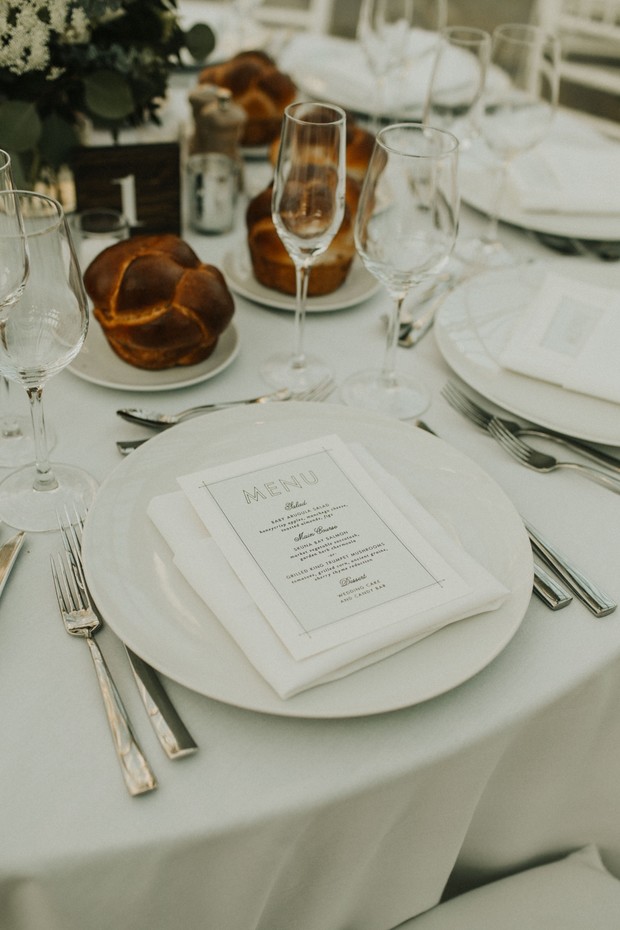 Elegant wedding table setting with bread and menu on a white plate