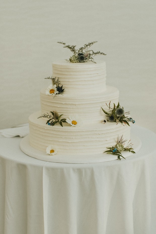 Elegant three-tiered wedding cake decorated with fresh flowers