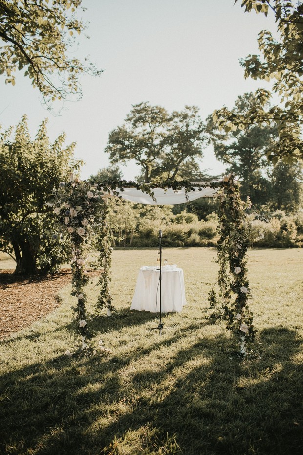 Wedding ceremony setup with floral archway and table outdoors
