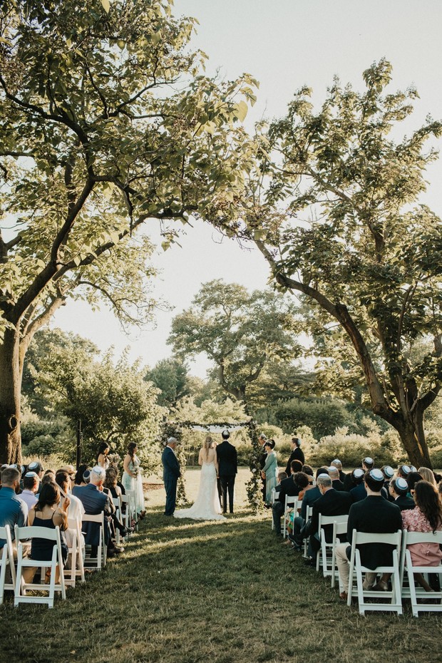 Outdoor Jewish wedding ceremony with couple under the trees