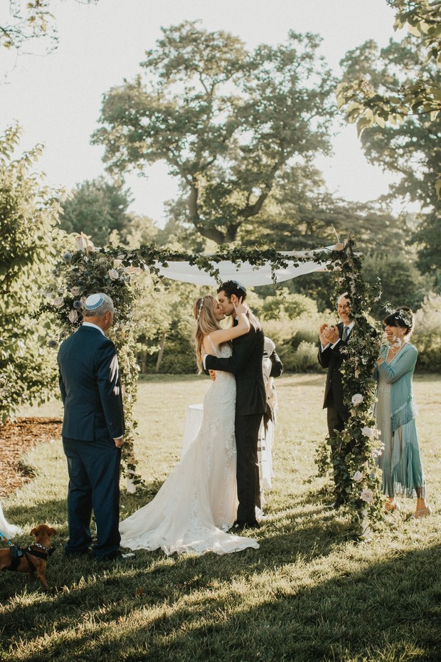 Bride and groom share a kiss at their outdoor wedding ceremony