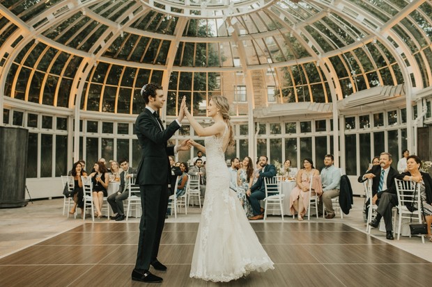 Elegant couple dancing at their wedding reception with guests watching
