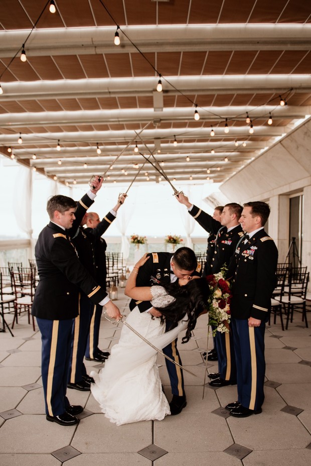 Military couple kissing under swords at wedding ceremony