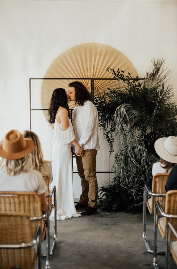 Boho chic wedding kiss with modern floral backdrop