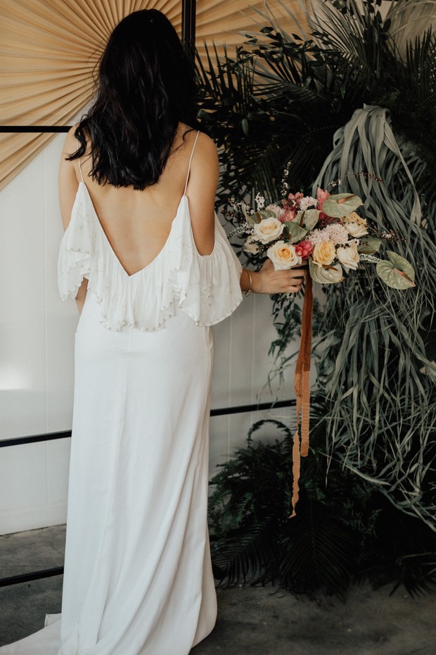 Bride in open back wedding dress with floral bouquet