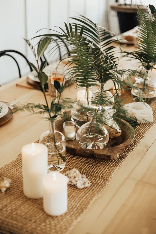 Elegant table centerpiece with candles and tropical leaves