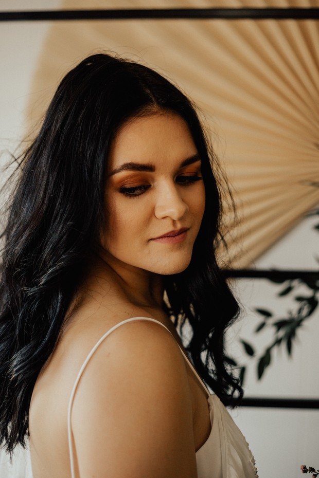 Woman with black hair and white dress looking down