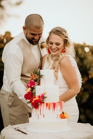 wedding couple with sunset accented wedding cake