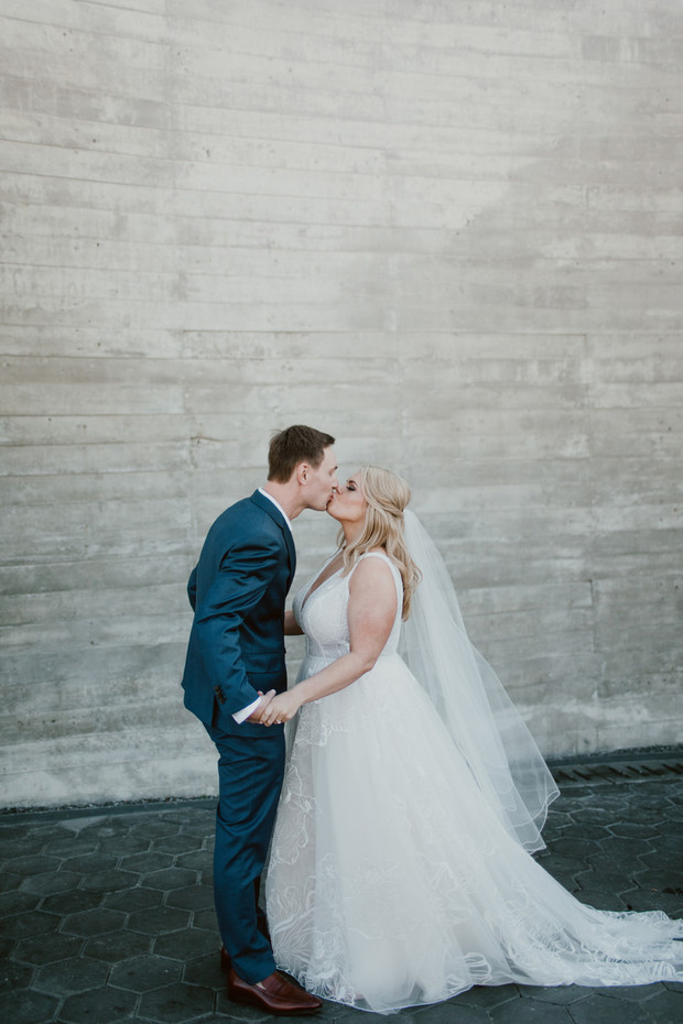 Newlyweds share a kiss in front of a textured wall