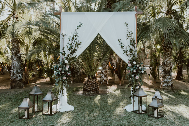 Palm tree wedding arch with lanterns and white fabric