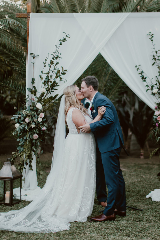 Newlyweds share a kiss at their outdoor wedding ceremony