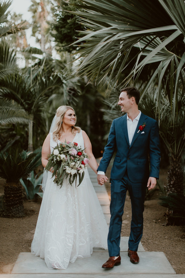 Bride and groom stroll hand in hand tropical wedding