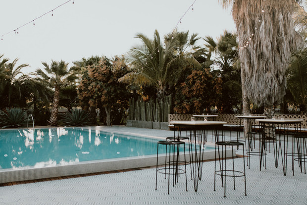 Outdoor pool area with palm trees and bar tables in a resort setting