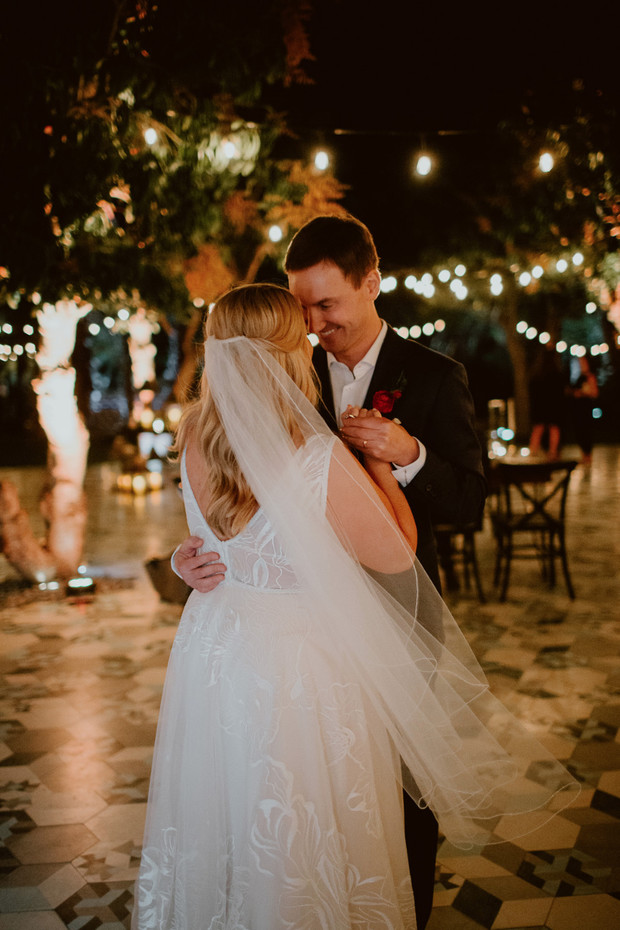 Bride and groom share a romantic dance under twinkling lights at night
