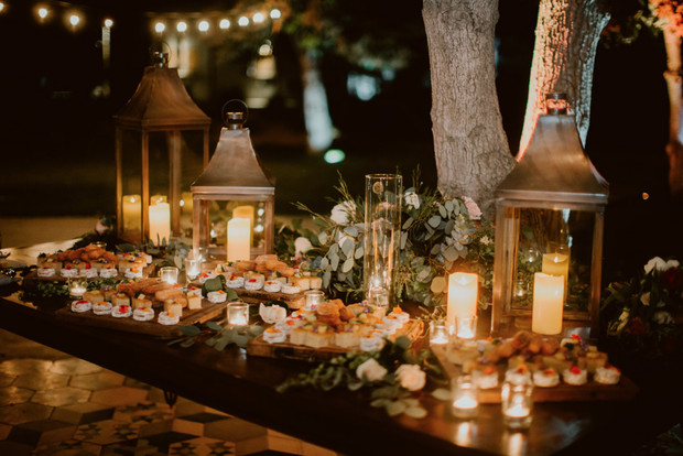 Elegant outdoor buffet table with candlelit lanterns and appetizers
