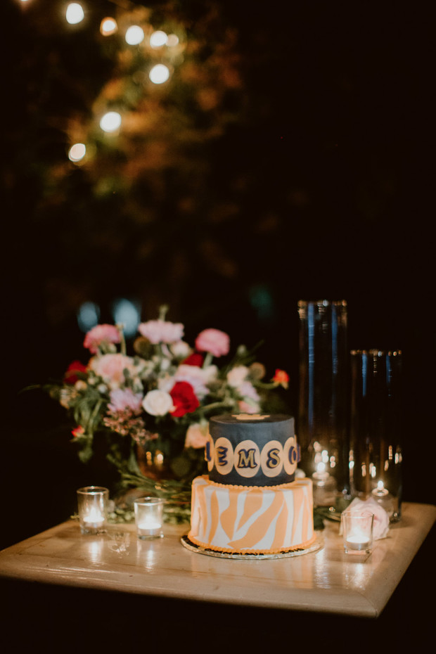 Elegant cake with EMSO on table with flowers and candles