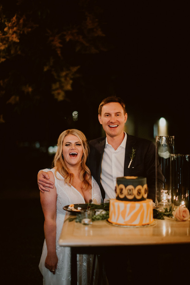 Joyful couple smiles as they celebrate their wedding with a cake