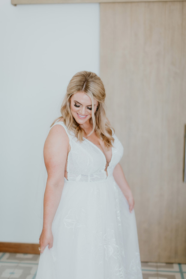 Blonde bride in white lace wedding dress smiles down