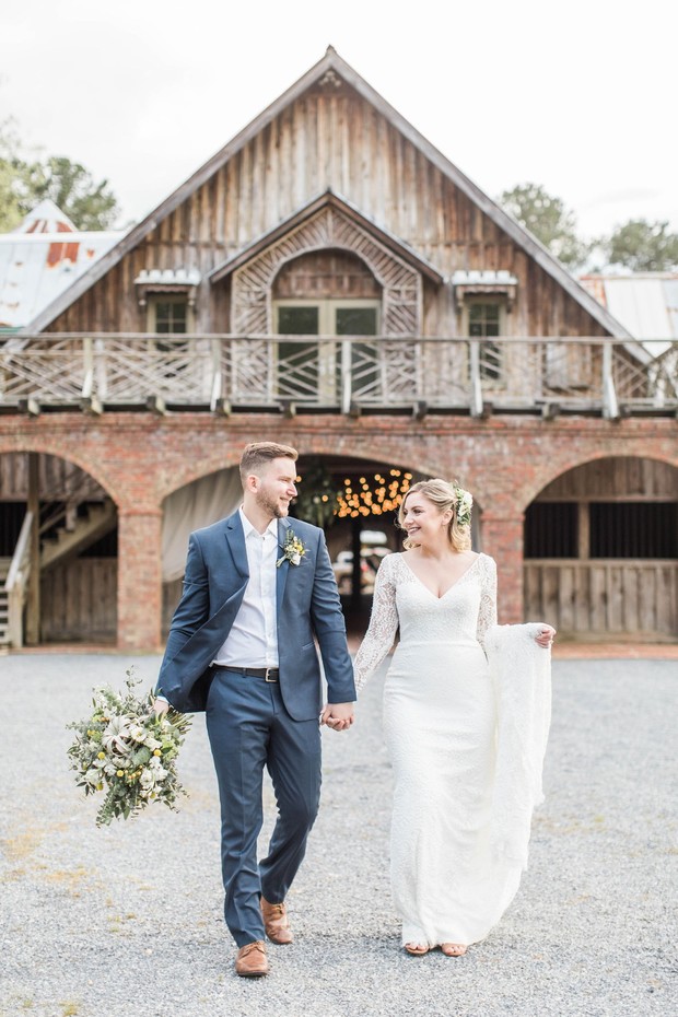 Bride and groom at barn wedding venue holding hands