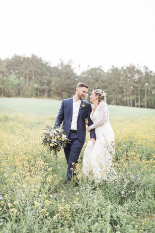 Newlyweds walking happily through a field of wildflowers together