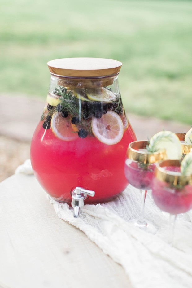 Refreshing pink lemonade drink in a dispenser with lemons