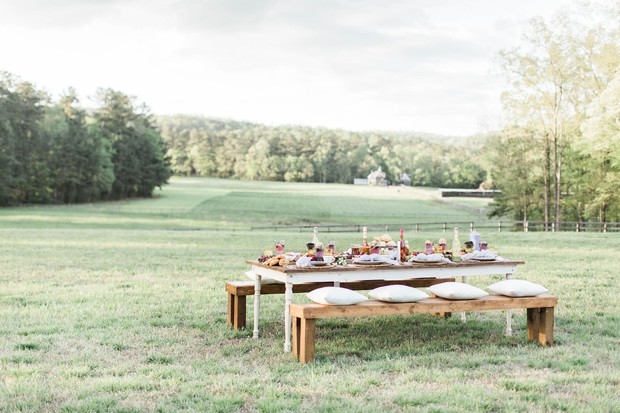 Outdoor dining table set with pillows in a grassy field