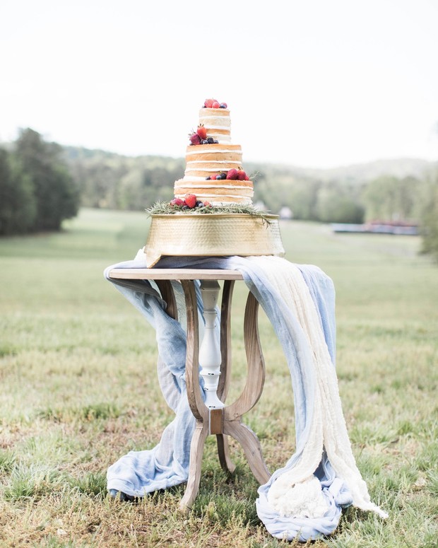 Rustic tiered cake with berries on a vintage table outdoors
