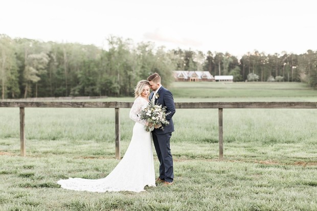Bride and groom embrace in rustic countryside setting