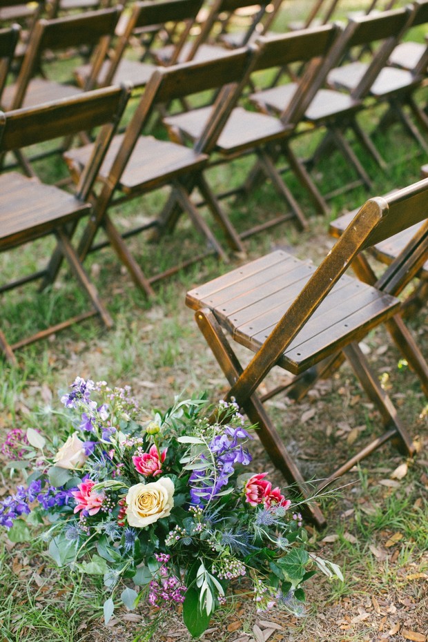 Outdoor wedding aisle with floral arrangements chairs