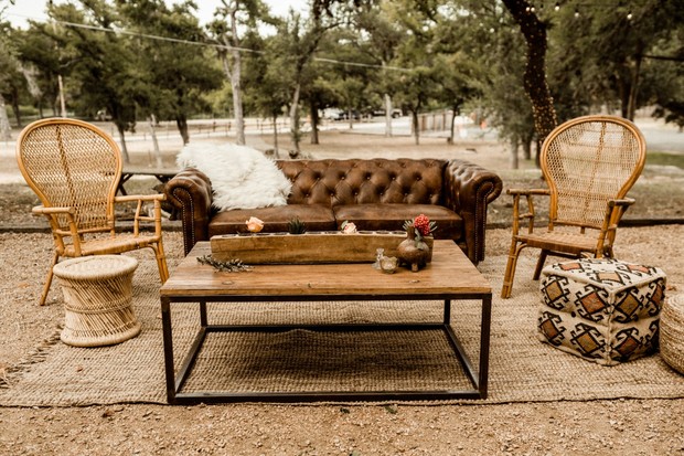 Rustic outdoor lounge setting with leather sofa and rattan chairs