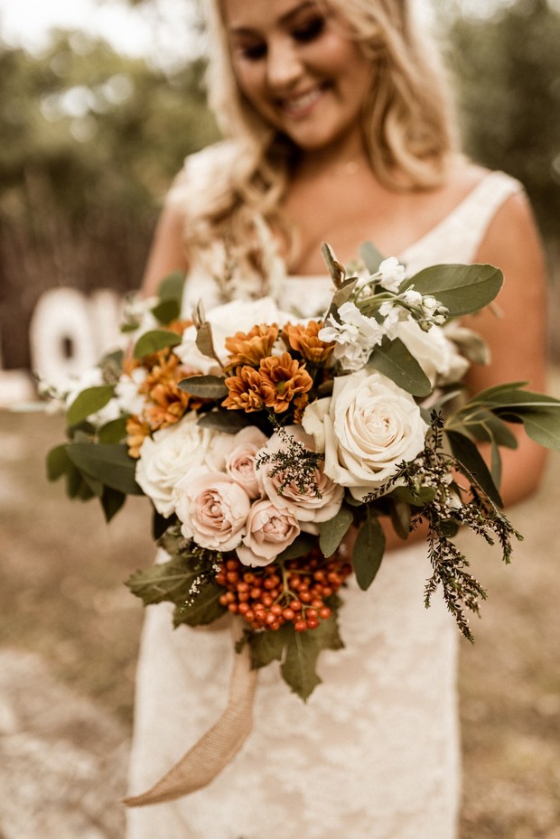 Happy bride holding a rustic orange and white bouquet