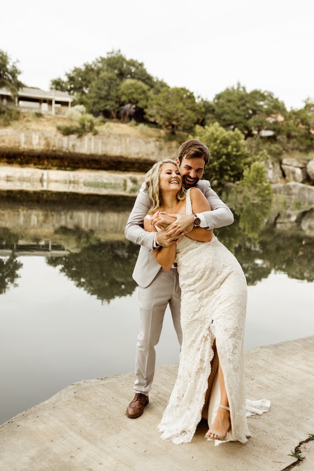 Happy bride and groom embracing by the lake on their wedding day