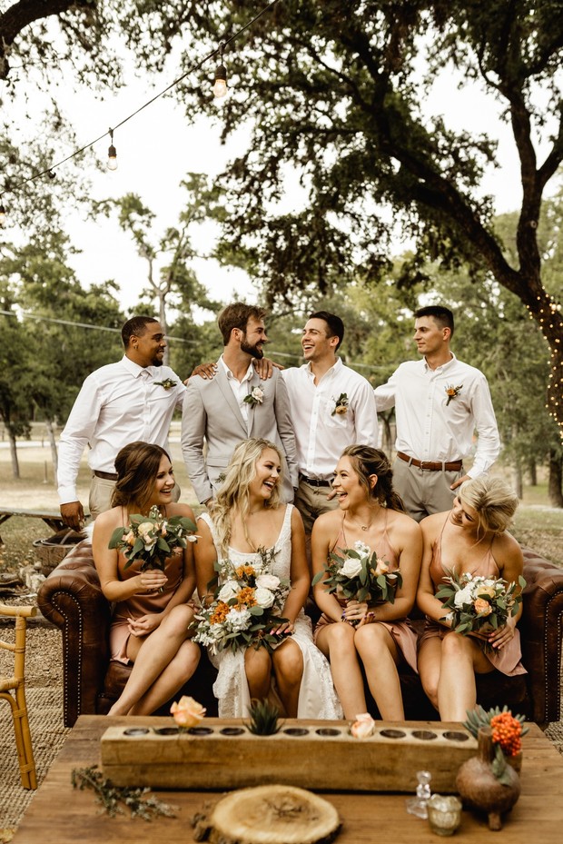 Happy wedding party smiling on rustic couch outdoors