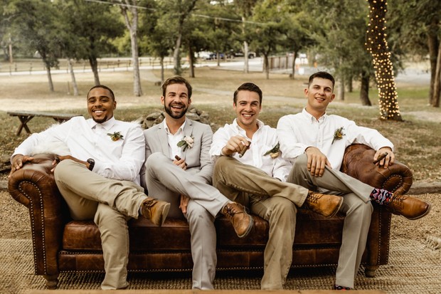 Groomsmen relax on a couch, enjoying cigars outdoors
