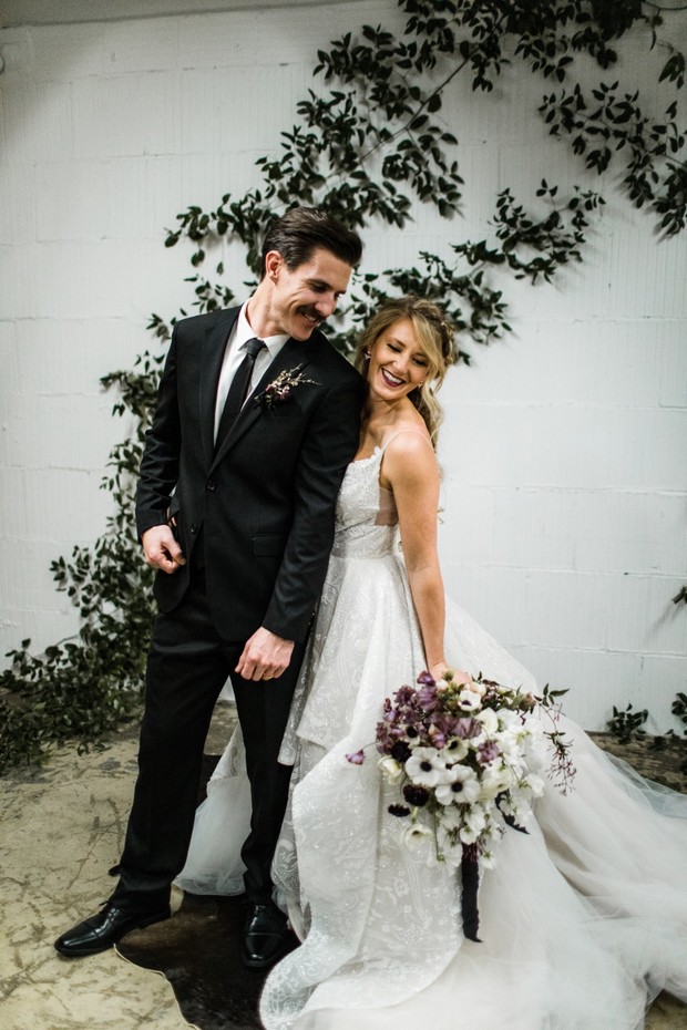 Bride and groom smile on wedding day with flower wall