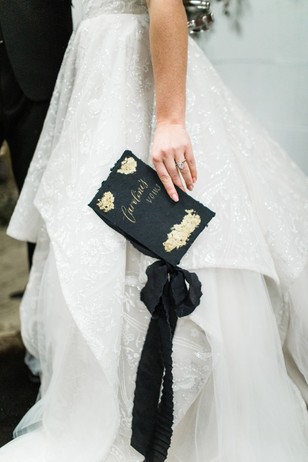 Bride holds wedding vows book with her elegant white dress