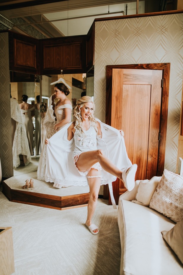 Playful bride in robe kicks leg up on wedding morning
