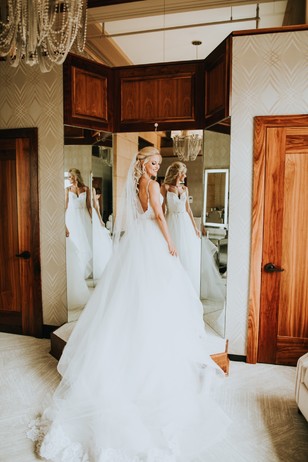 Bride in a white wedding dress admires herself in mirror