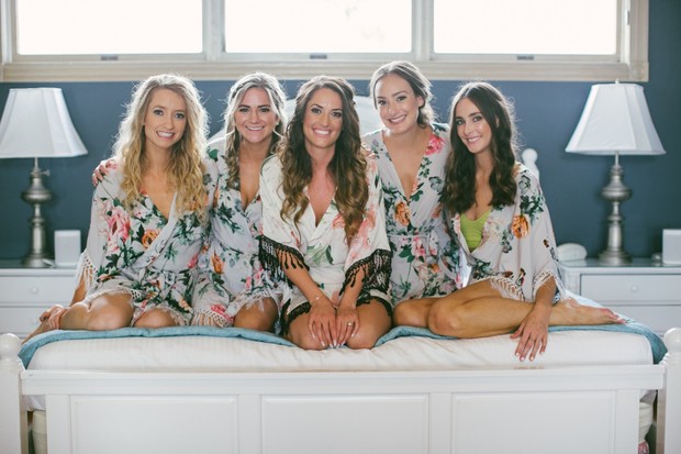 Bridesmaids in floral robes on a bed, ready for wedding day