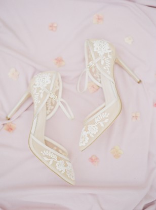 Elegant ivory lace bridal heels on pink silk fabric