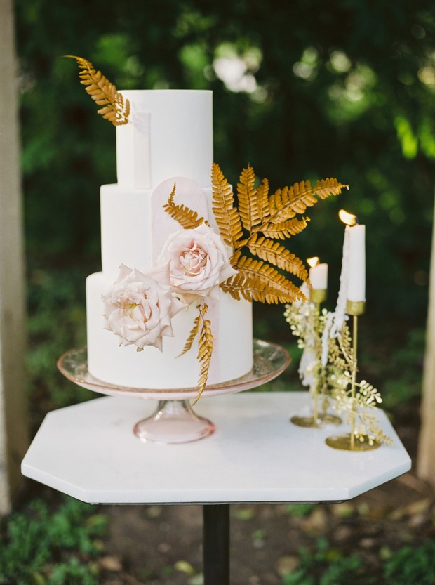 Elegant white wedding cake with gold foliage and roses