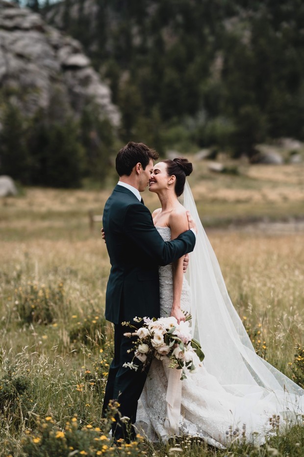 Bride and groom embrace in a scenic field