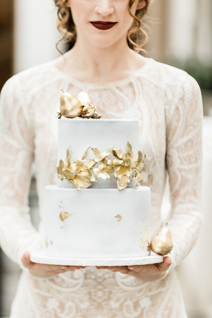 Woman holding a two tier wedding cake with gold accents