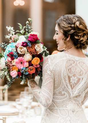 Bride in lace dress holding vibrant wedding bouquet